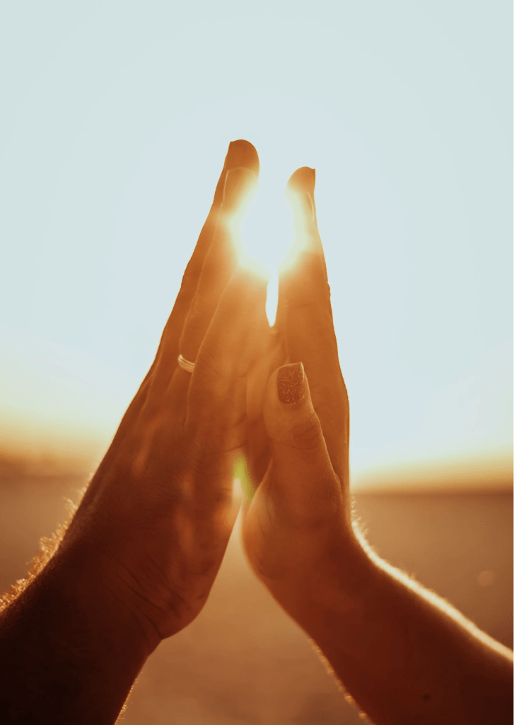 Loving couple touching hands against bright sunset